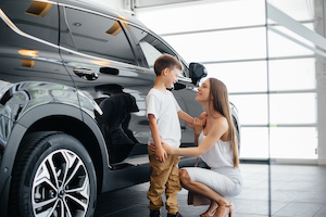 En glad mamma med sin son son väljer en ny bil hos en bilhandlare